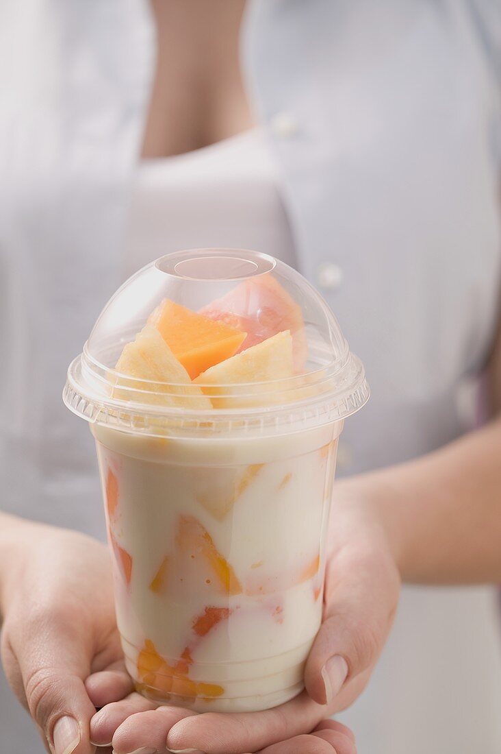 Woman holding fruit yoghurt in plastic pot