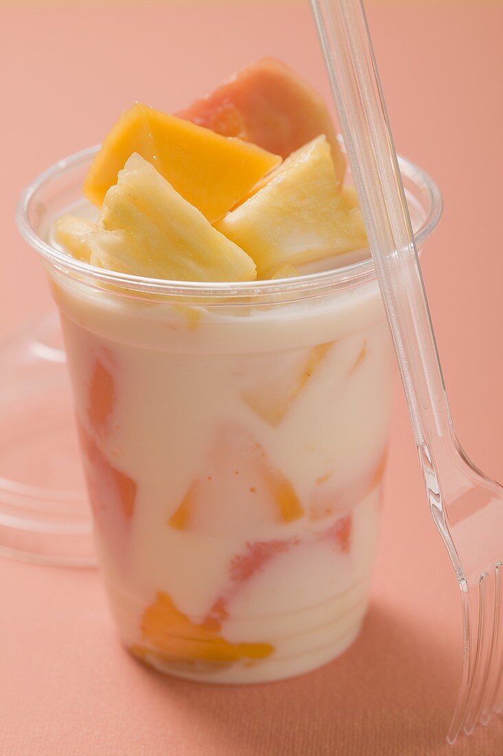 Joghurt mit frischen Früchten im Plastikbecher, daneben Gabel