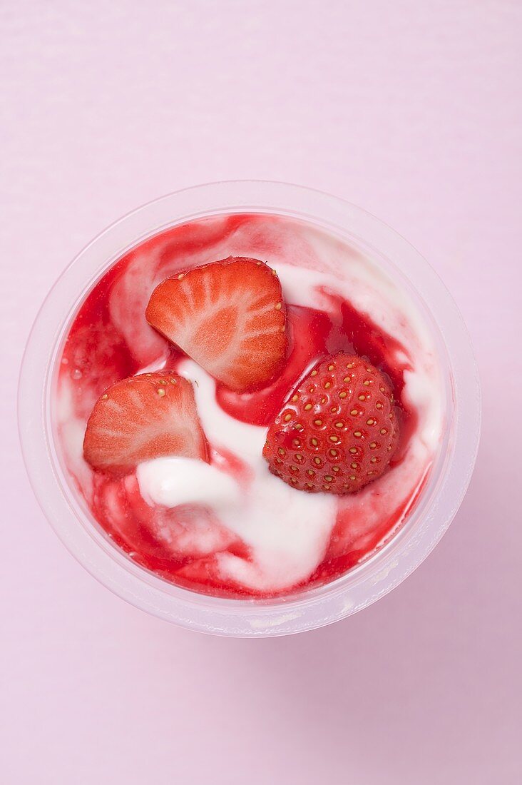 Strawberry yoghurt in plastic pot (overhead view)