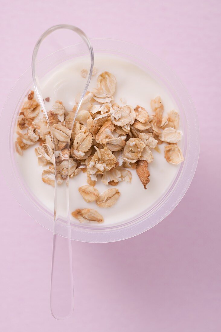 Joghurt mit Cerealien im Plastikbecher mit Löffel