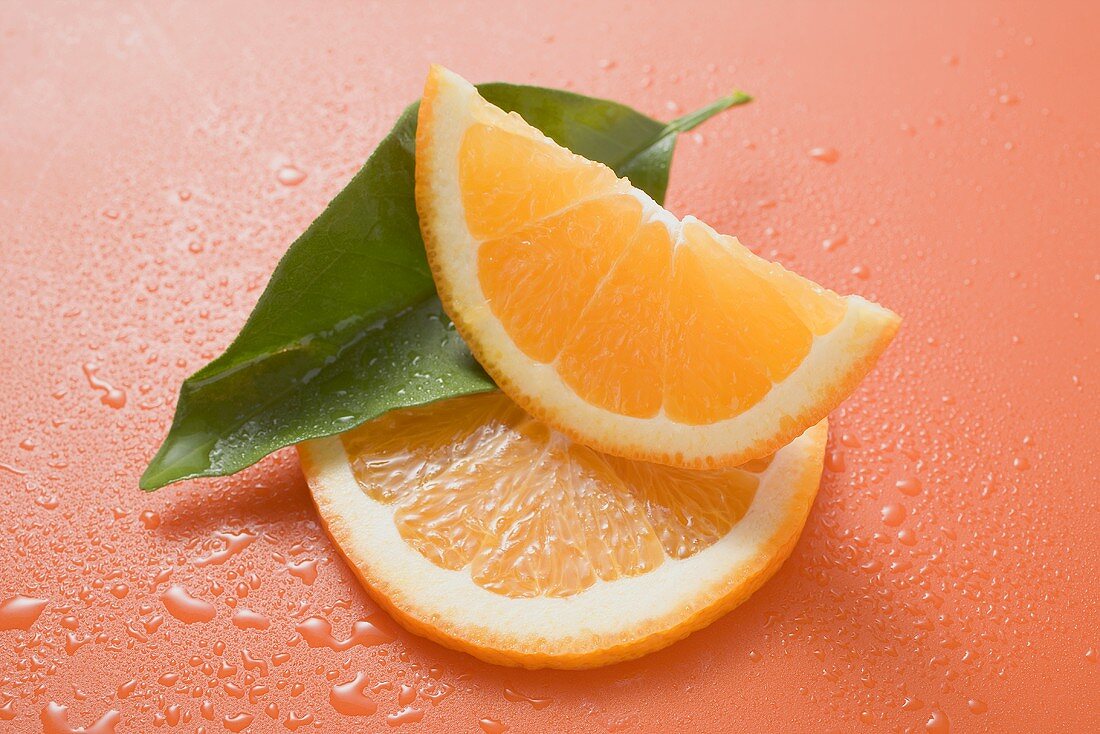 Orange wedge, orange slice and leaf with drops of water