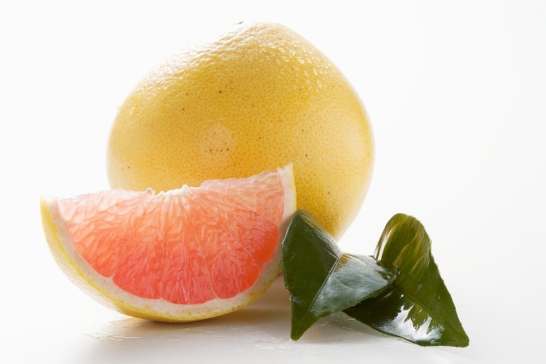 Whole grapefruit, wedge of pink grapefruit and leaves