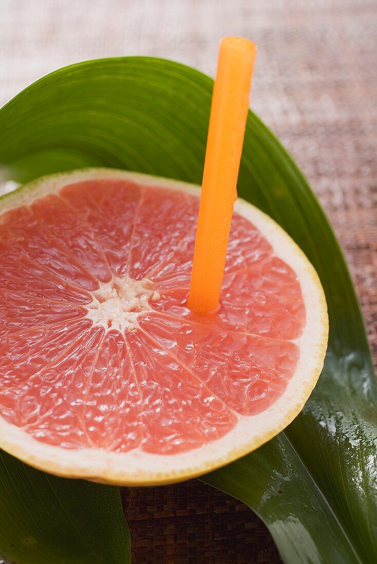 Half a pink grapefruit with a straw