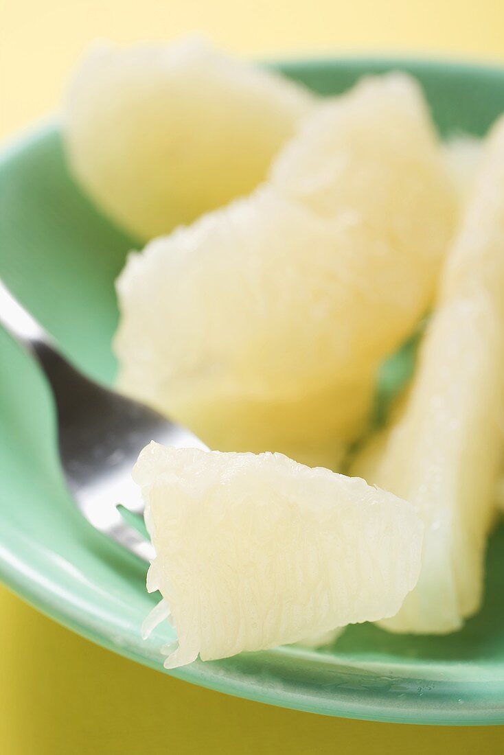 Grapefruitfilets auf Teller und Gabel