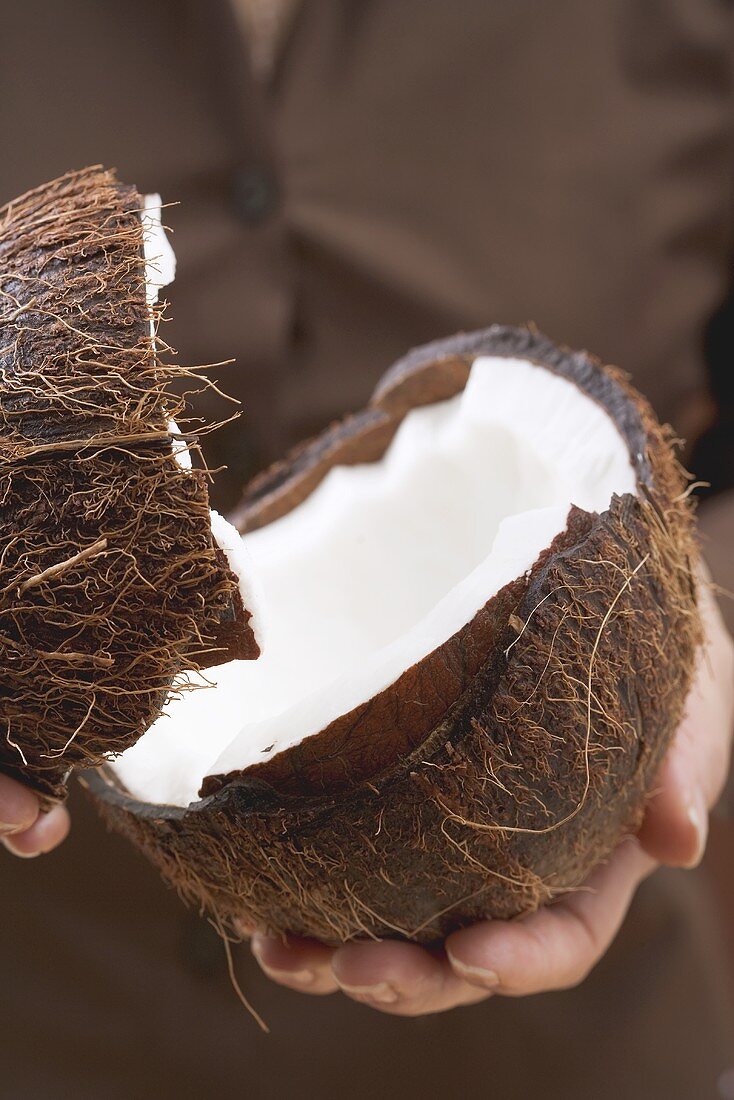 Hands holding halved coconut