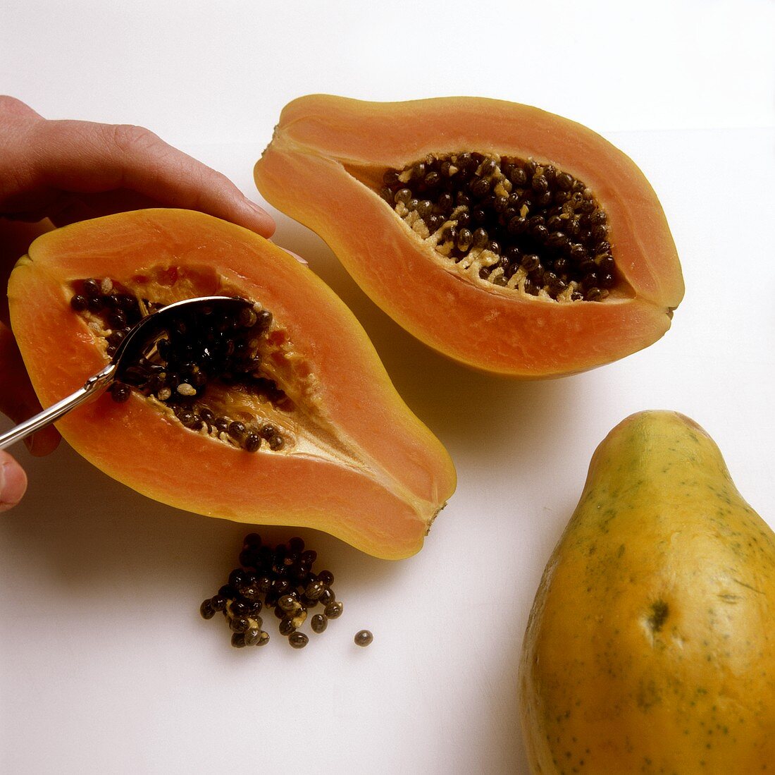 Scraping out papaya seeds with a spoon
