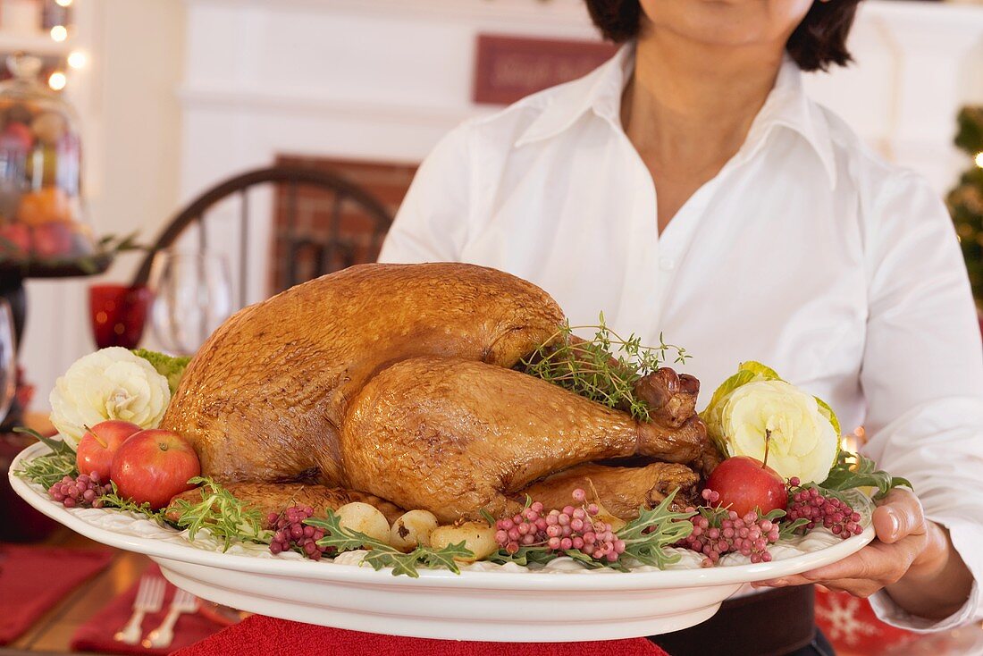 Frau serviert gebratenen Turkey zu Weihnachten