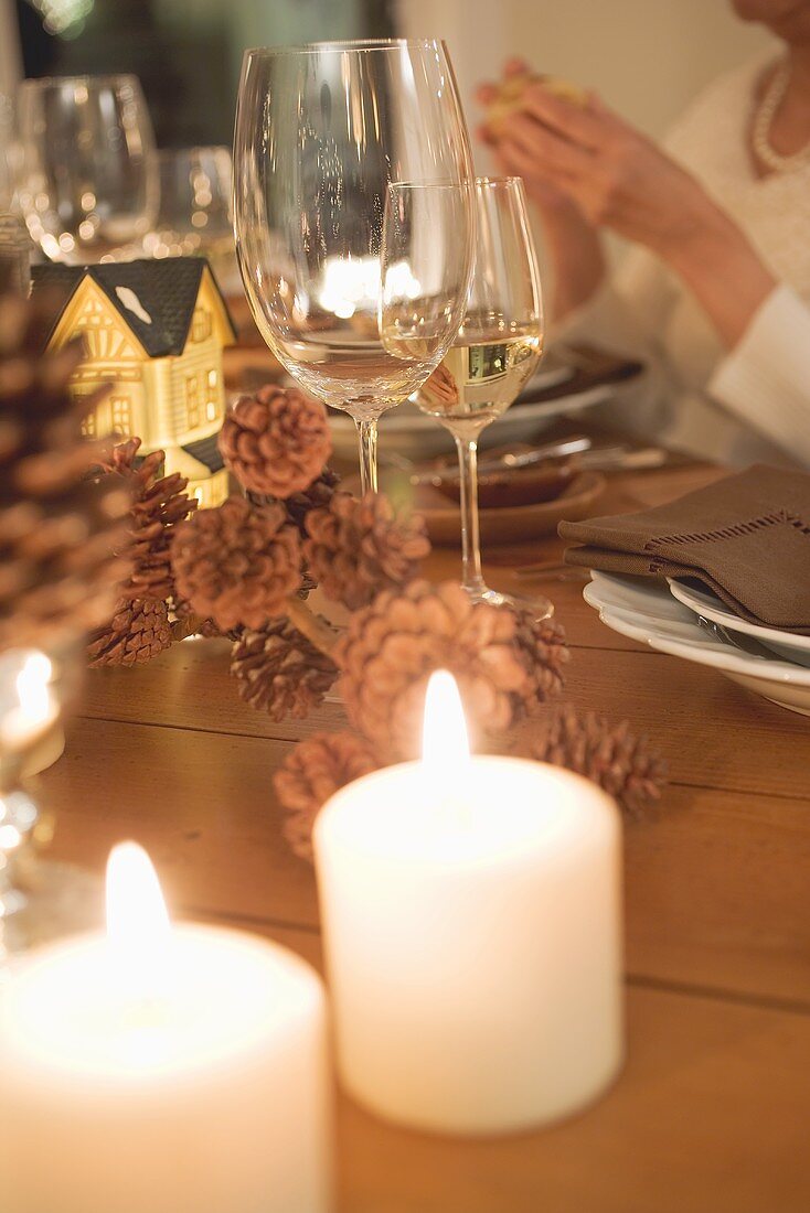 Weingläser und Kerzen am Weihnachtstisch, Frau im Hintergrund