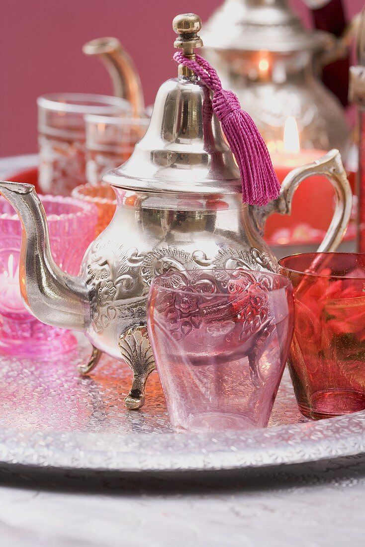 Silver teapot, glasses and windlights on tray