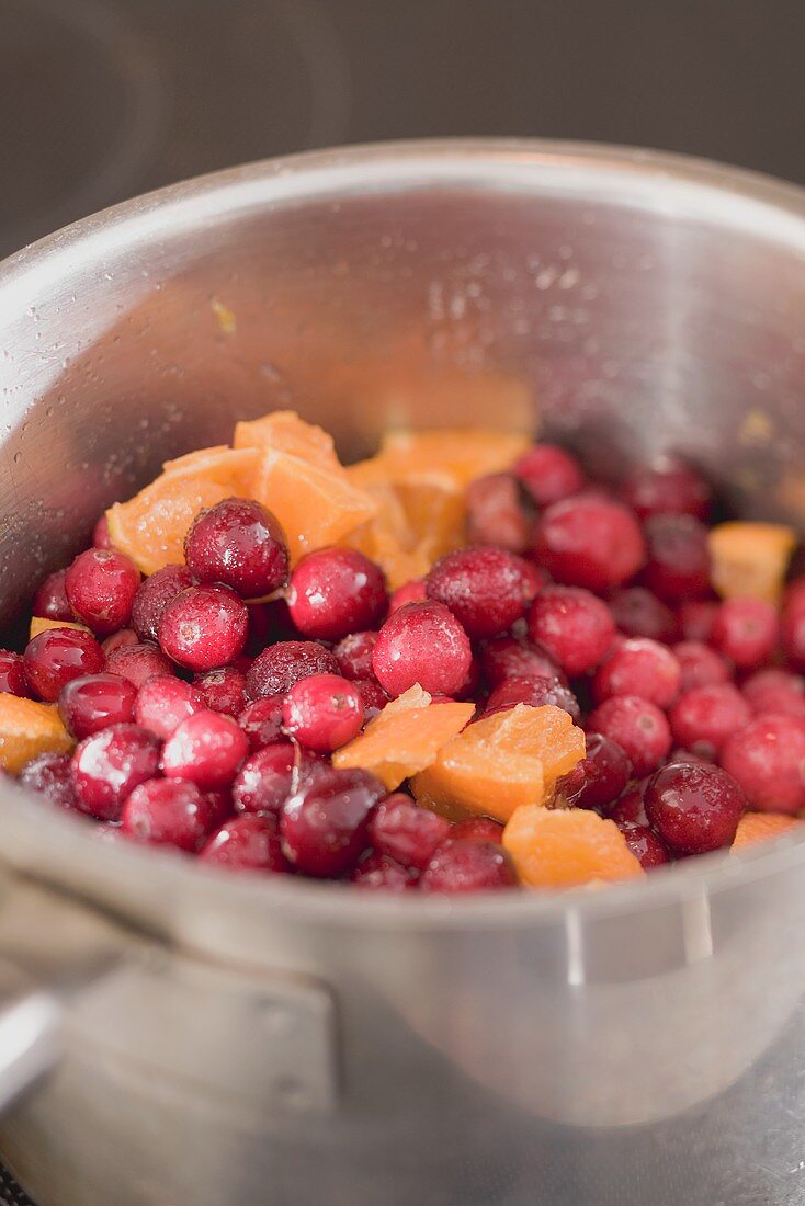 Cranberrysauce zubereiten: Cranberries mit Orangen im Topf