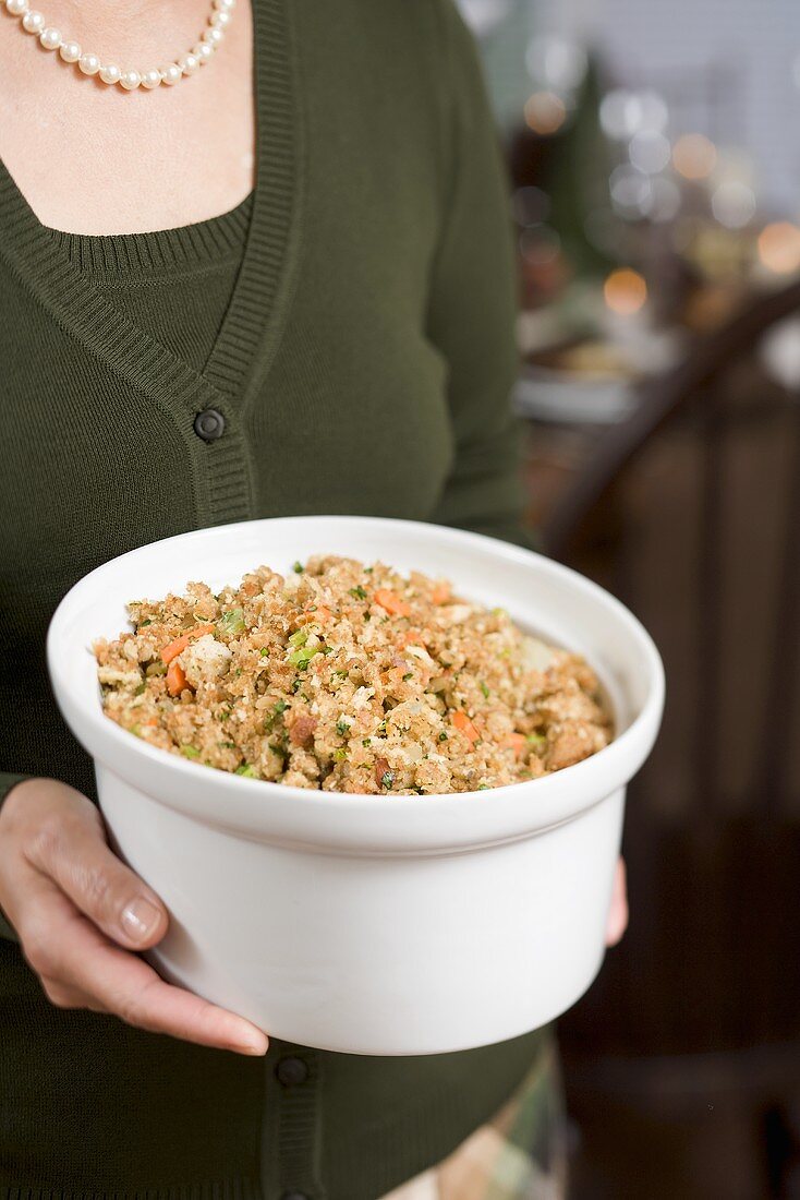 Woman holding large dish of bread stuffing (Christmas)