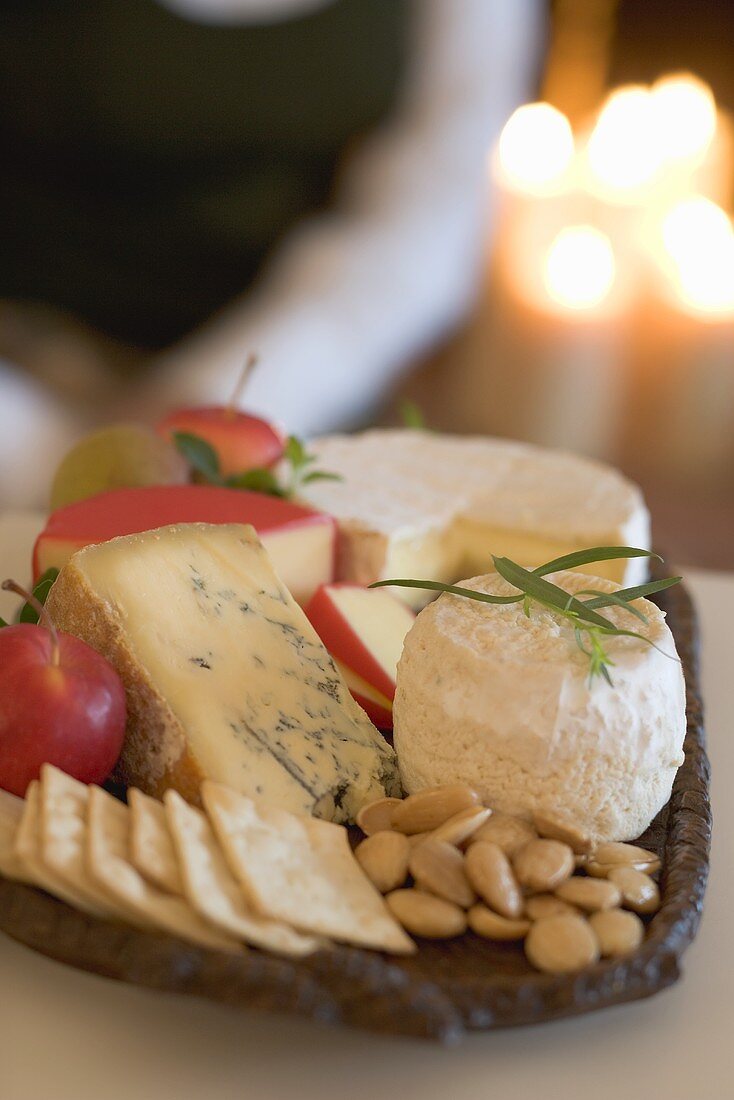 Cheeseboard with fruit and crackers, woman in background