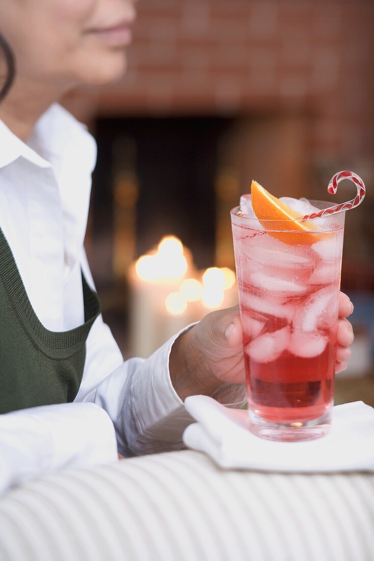 Frau auf Sofa hält Glas Campari mit Eiswürfeln