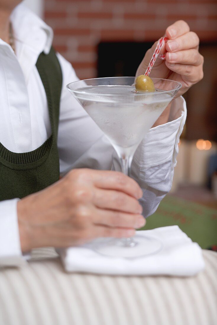 Woman holding glass of Martini with olive