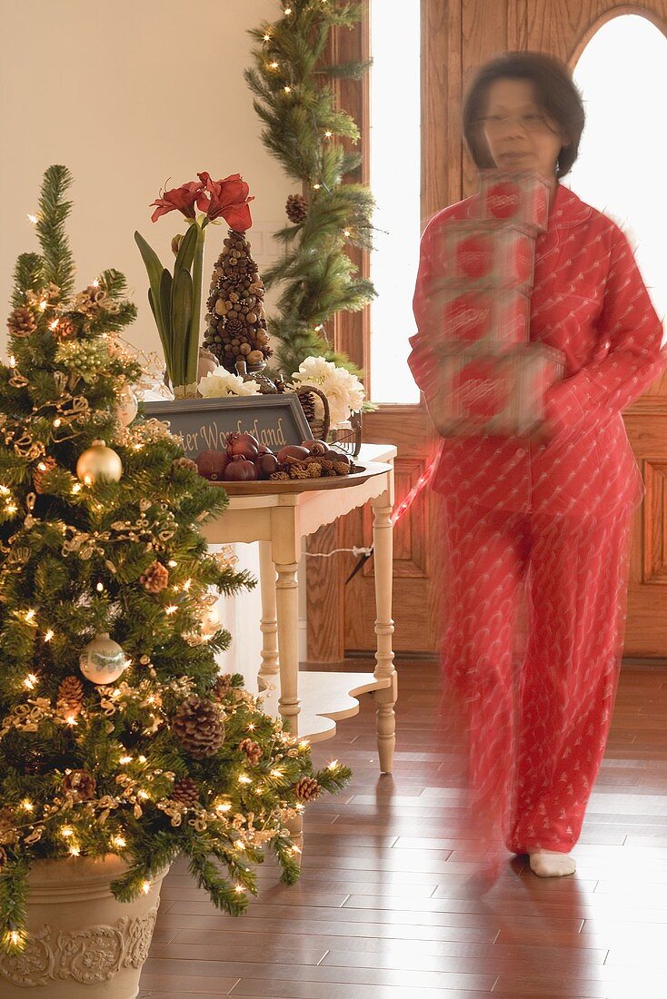 Woman carrying boxes of Xmas decorations through living room