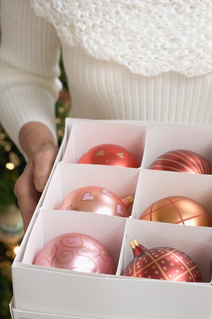 Frau hält Schachtel mit Christbaumkugeln