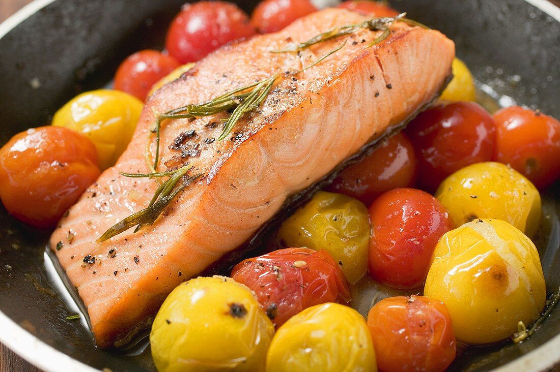 Fried salmon fillet and cherry tomatoes in frying pan