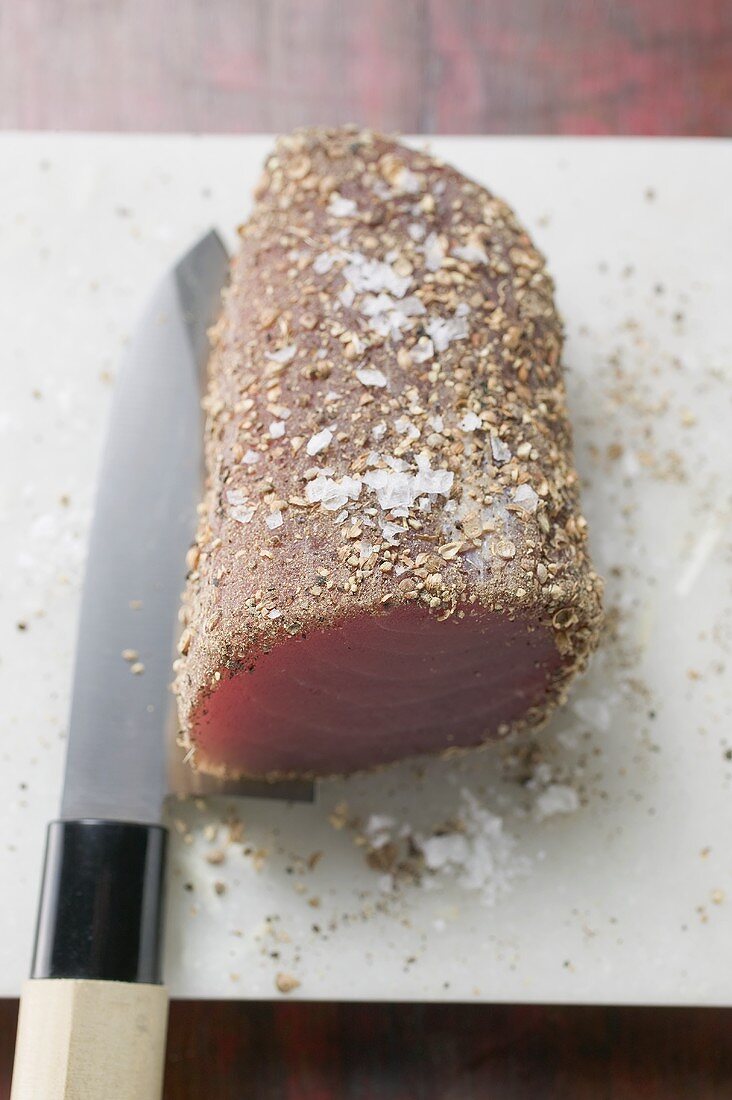 Raw tuna fillet with salt and pepper on knife