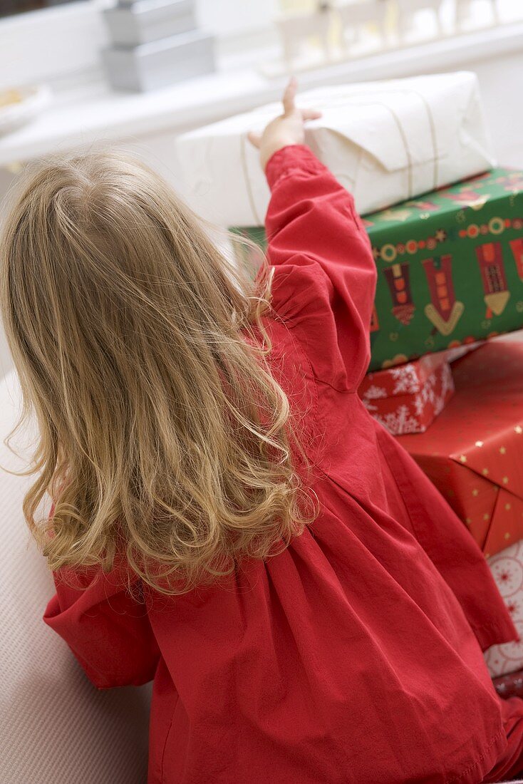 Kleines Mädchen vor gestapelten Weihnachtspaketen