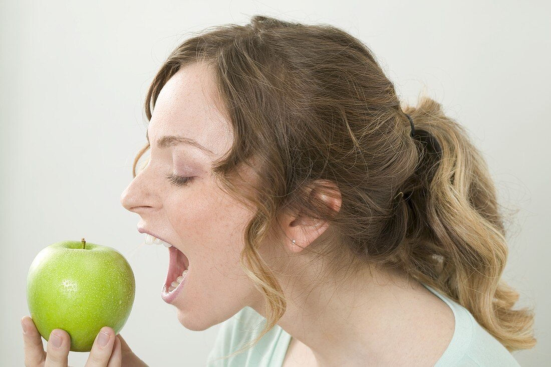 Frau beisst in grünen Apfel