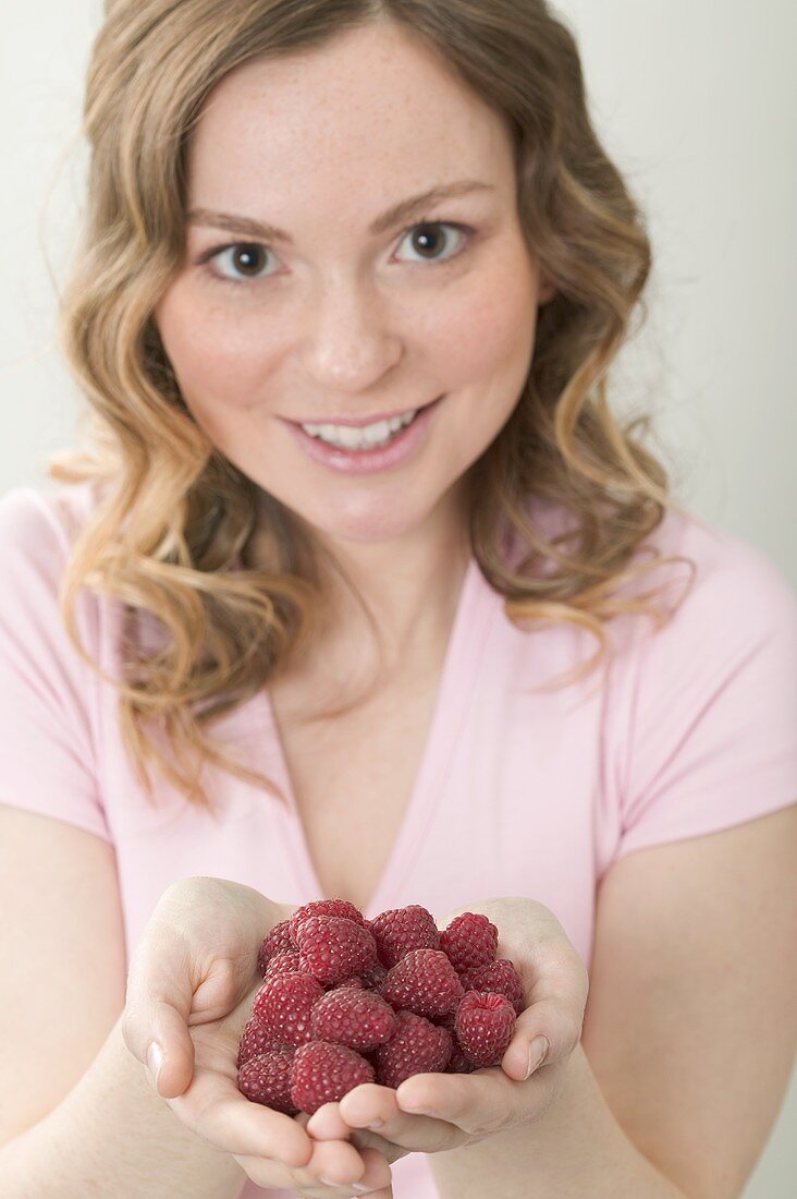 Woman holding fresh raspberries