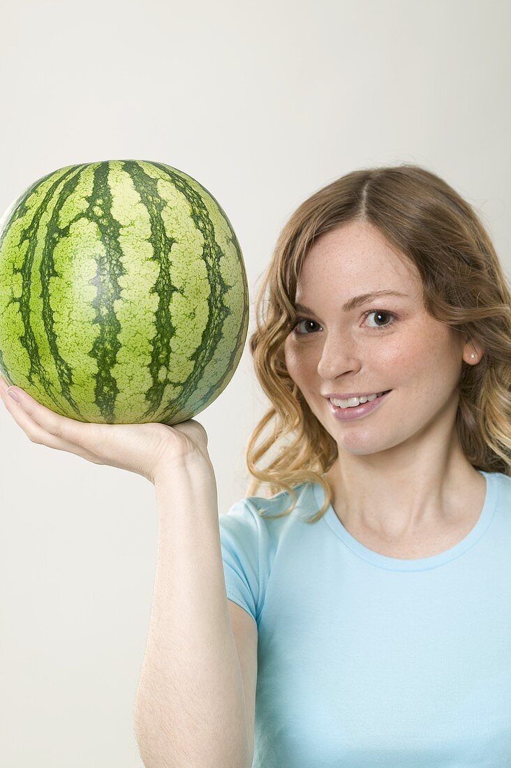 Frau hält Wassermelone mit einer Hand
