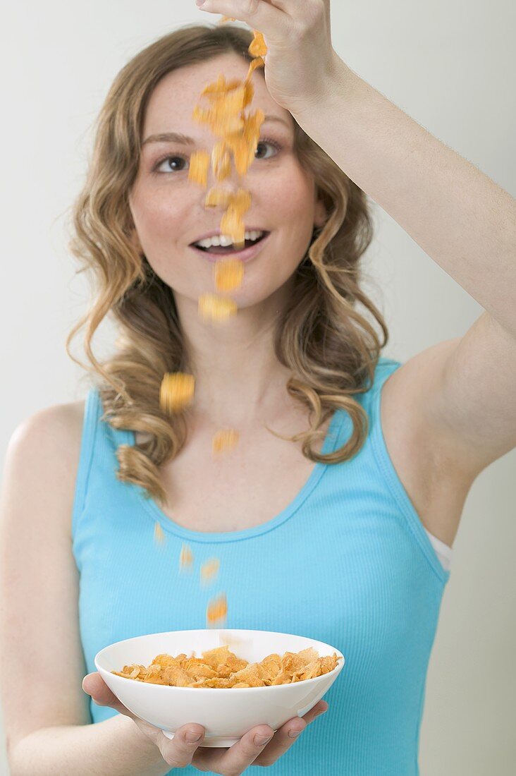 Frau schüttet Cornflakes in Schale