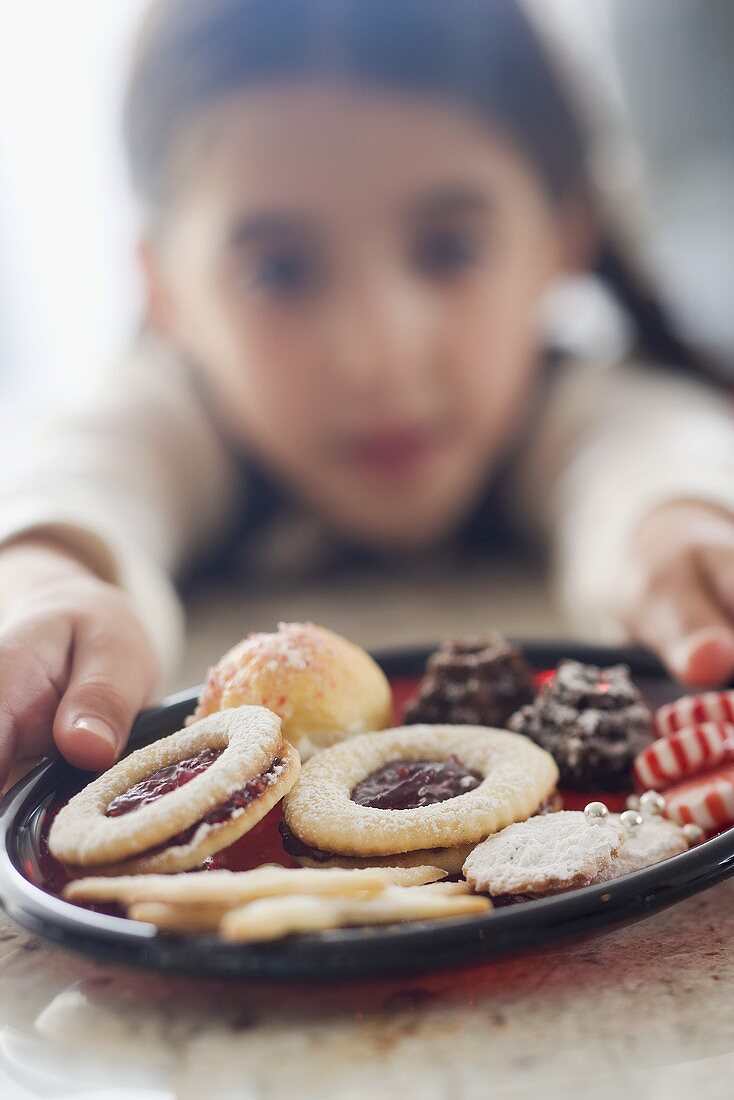 Girl reaching for plate of biscuits