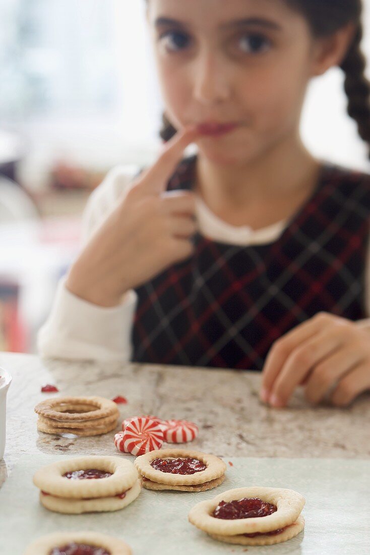 Girl sucking jam from her finger while making biscuits