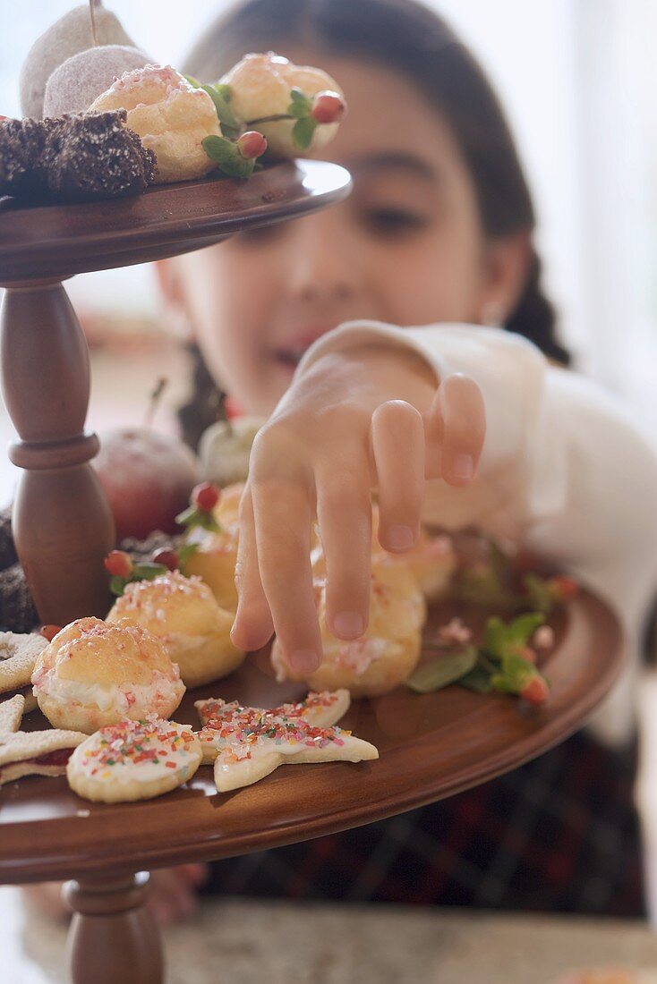 Mädchen greift nach Weihnachtsplätzchen auf Etagere