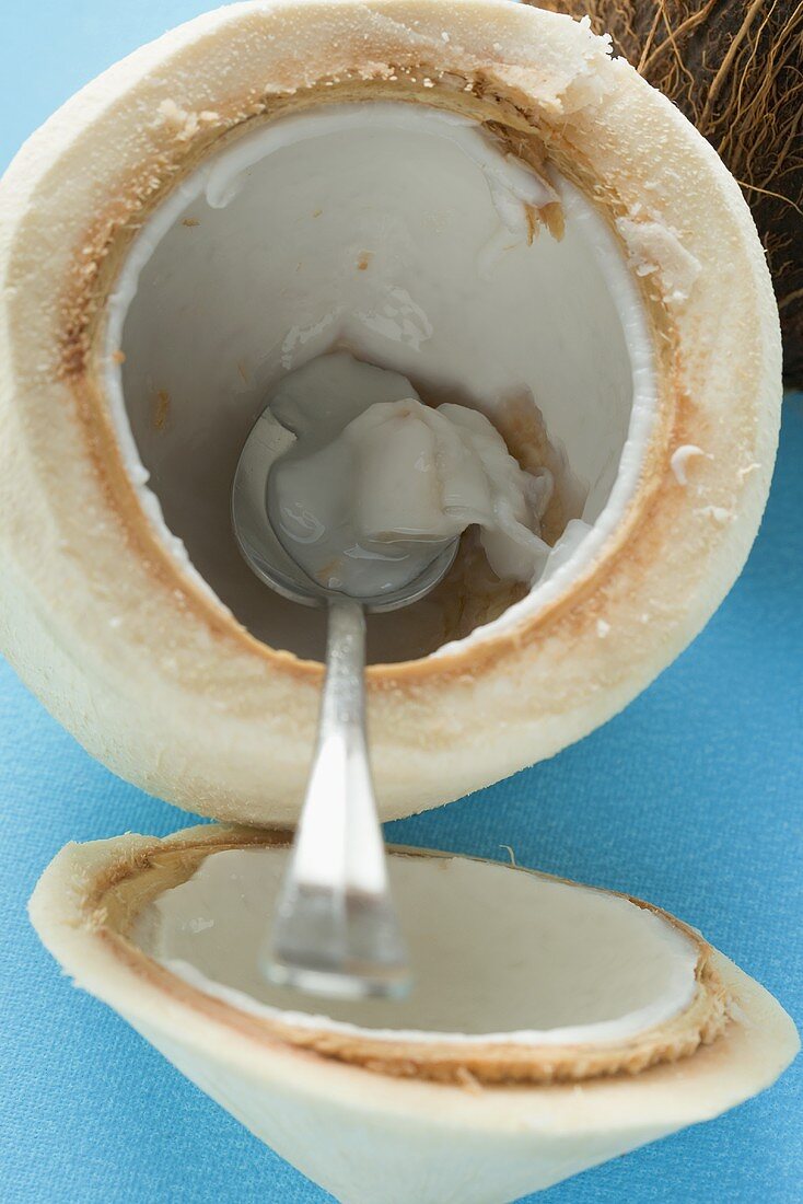 Coconut, shelled and hollowed out, with spoon