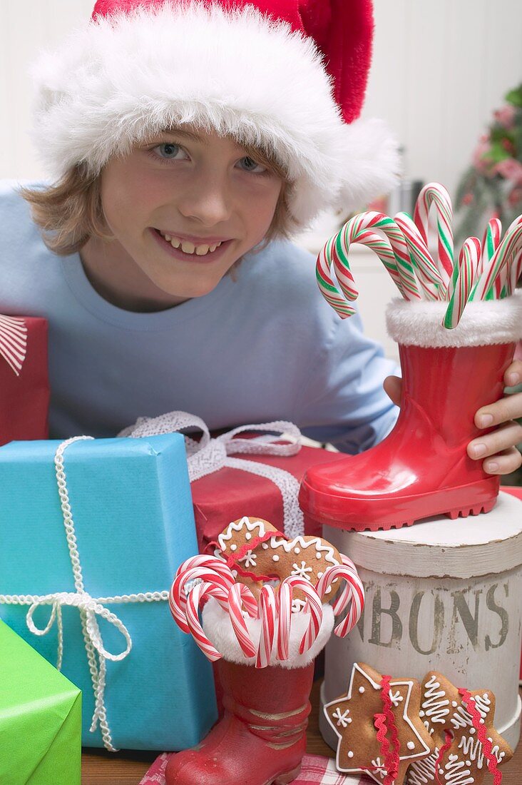 Junge mit Weihnachtsmütze und Geschenken