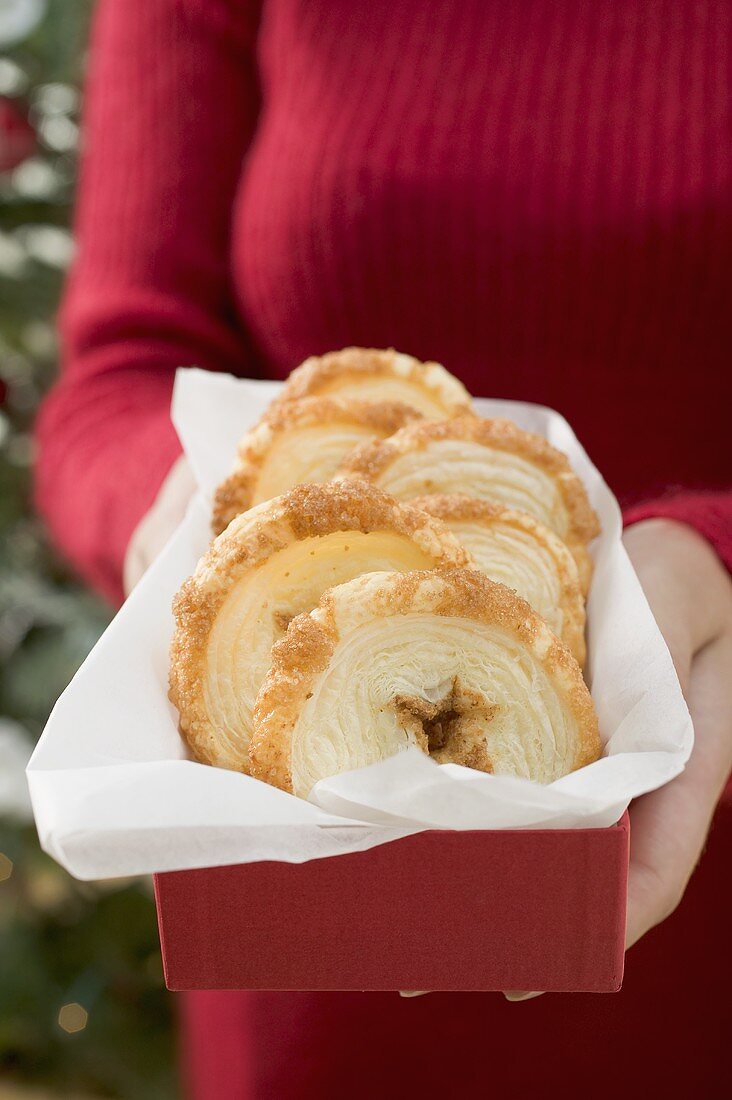 Woman holding palmiers (puff pastry biscuits) in box