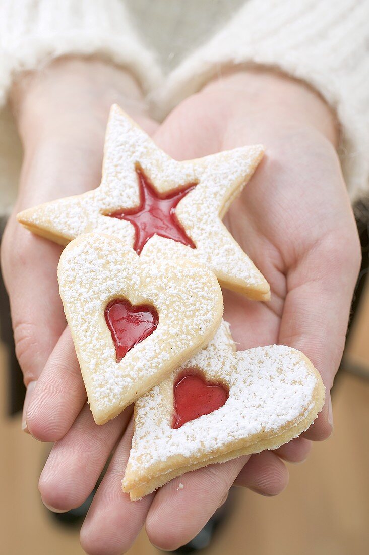 Hands holding three jam biscuits