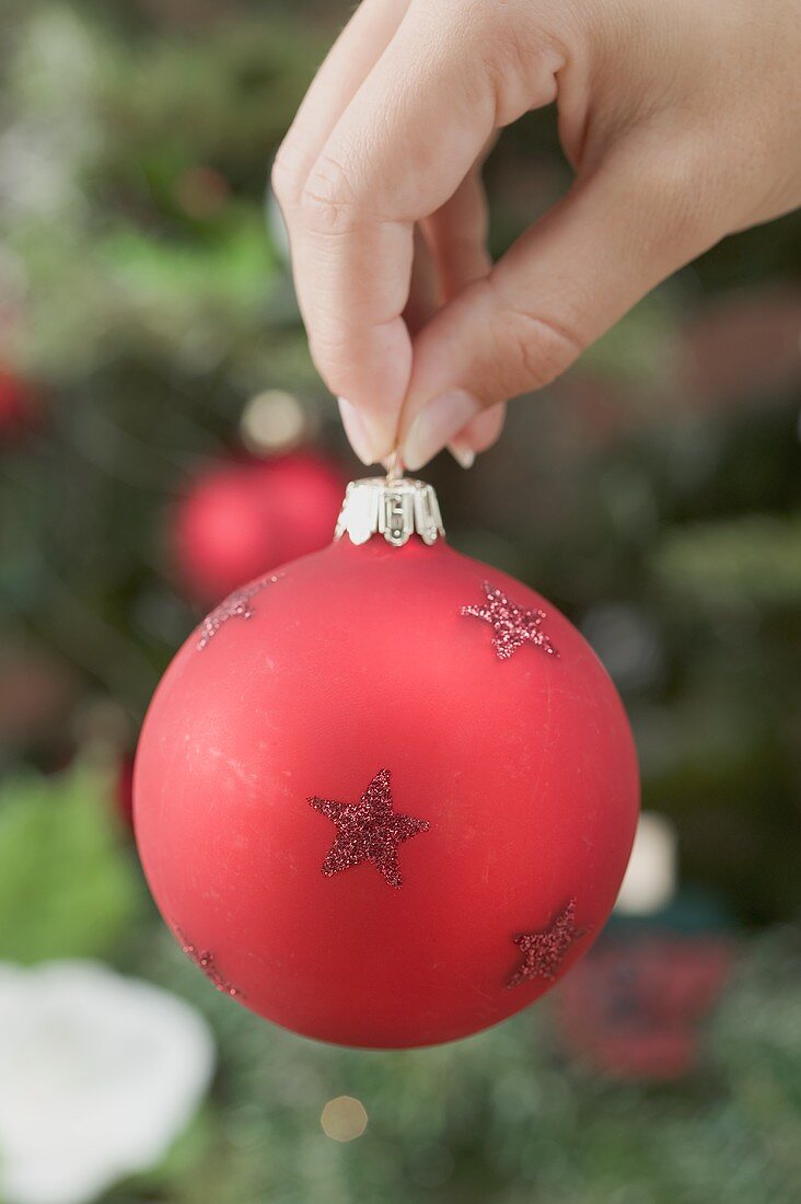 Hand hält rote Christbaumkugel