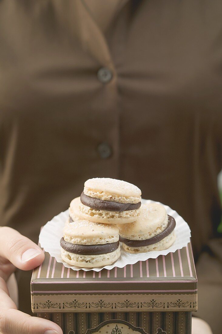 Woman holding macarons (small French cakes) on box