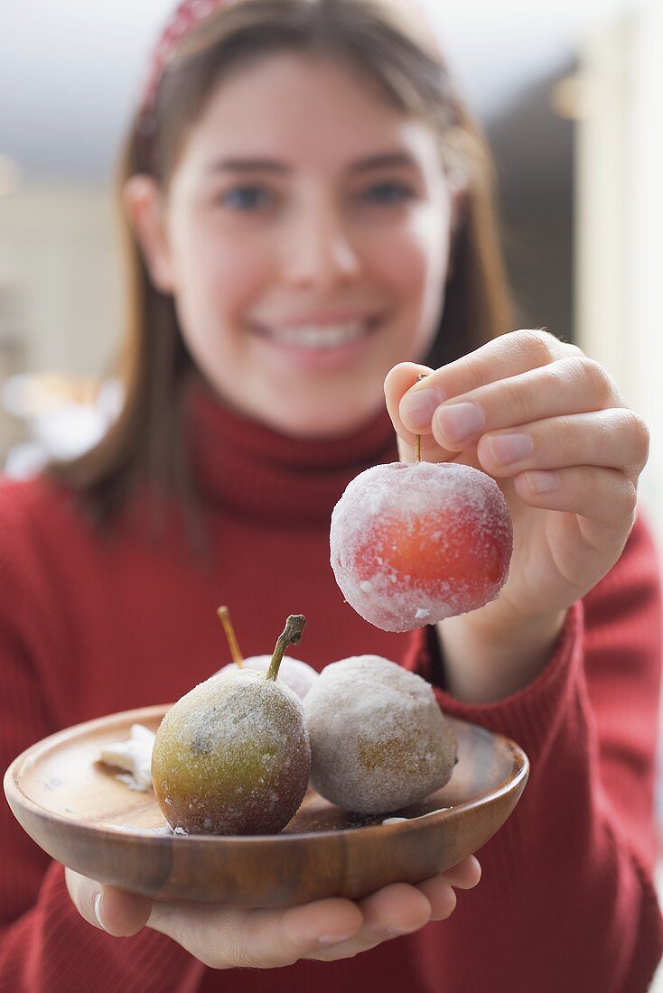 Young woman holding sugared fruit