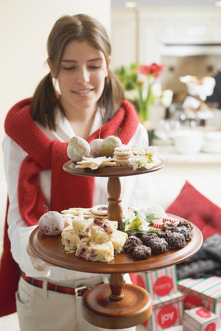 Junge Frau hält Etagere mit Weihnachtsgebäck