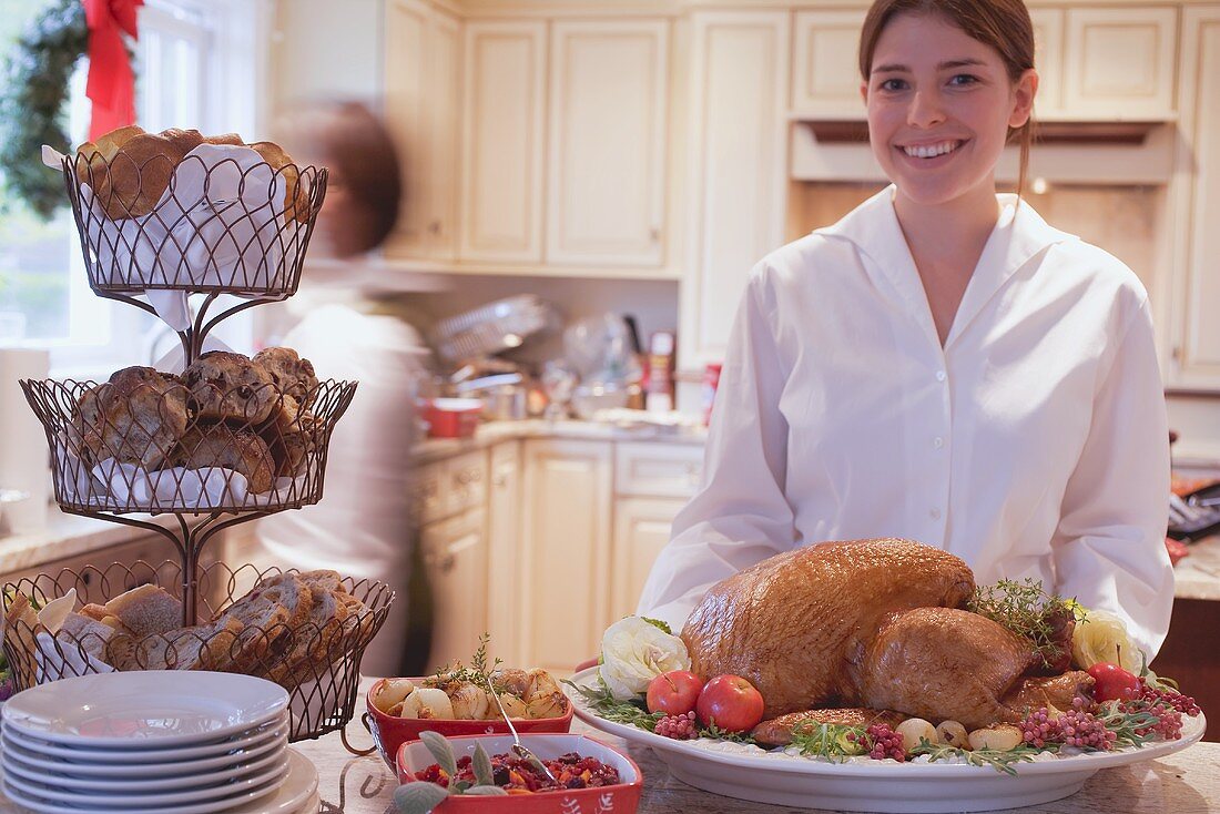 Young woman in kitchen with roast turkey for Christmas