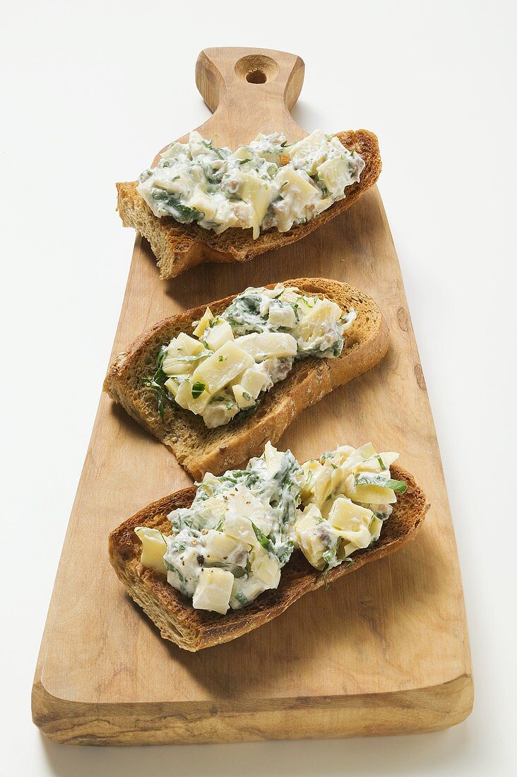 Artichokes and basil on toast on chopping board