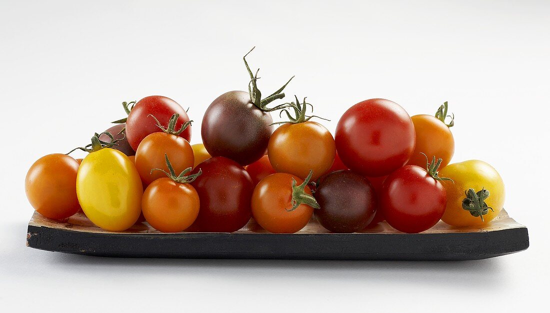 Tomatoes of various colours on wooden plate