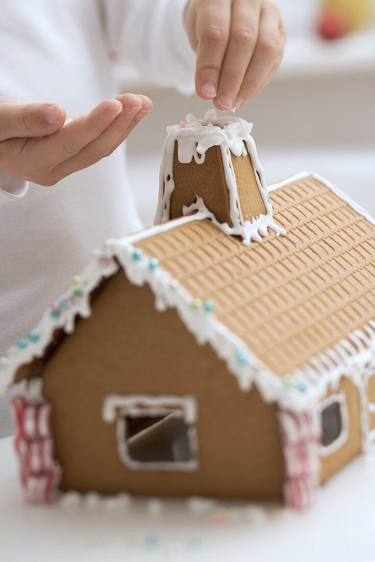 Child decorating gingerbread house