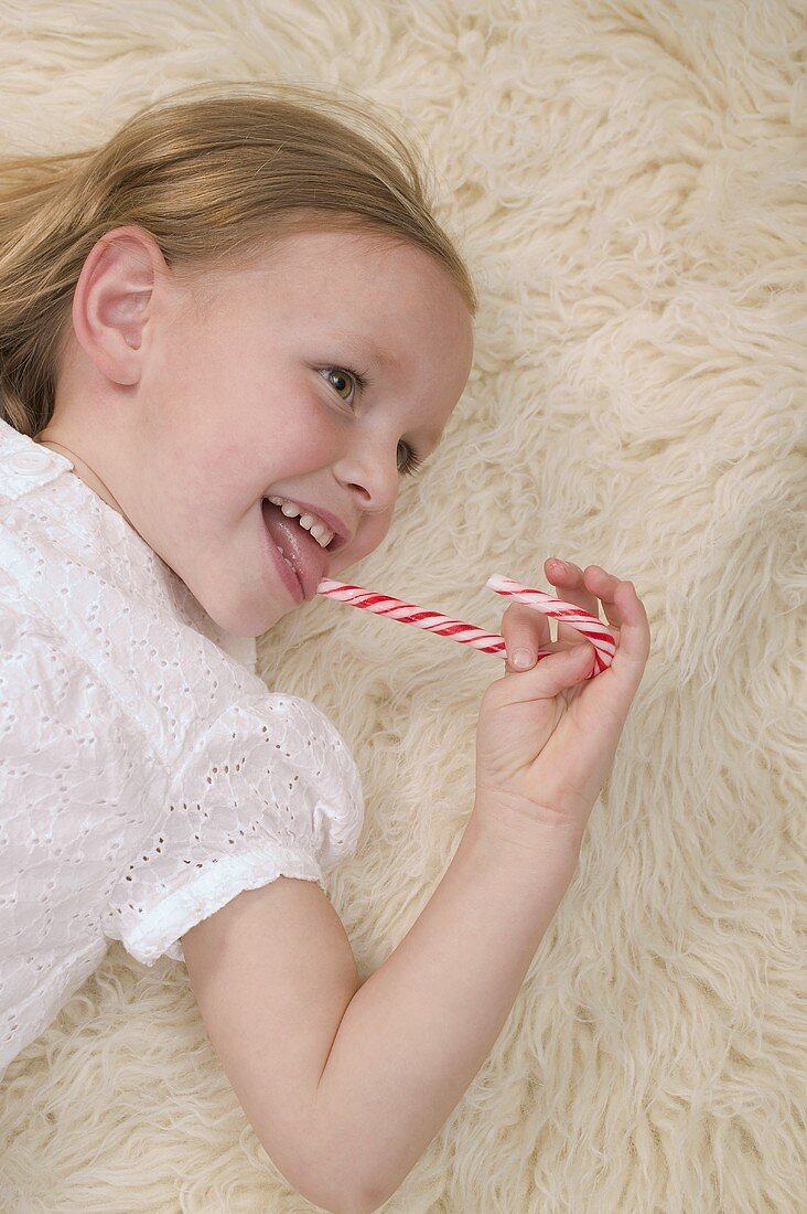 Small girl eating candy cane