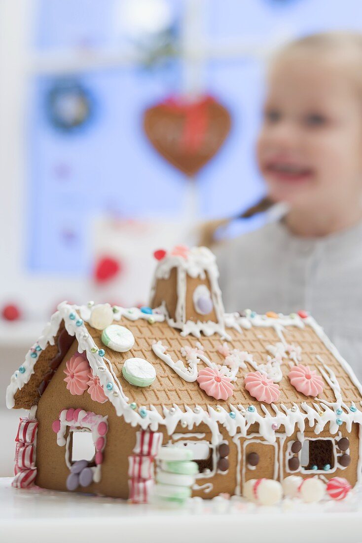 Decorated gingerbread house, small girl in background