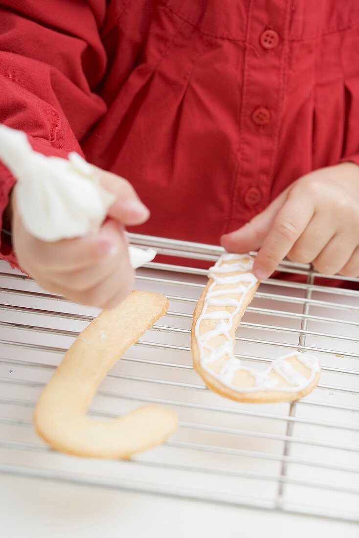 Kleines Mädchen verziert Weihnachtsplätzchen mit Spritztüte