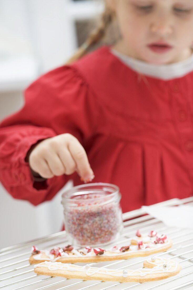 Kleines Mädchen verziert Weihnachtsplätzchen