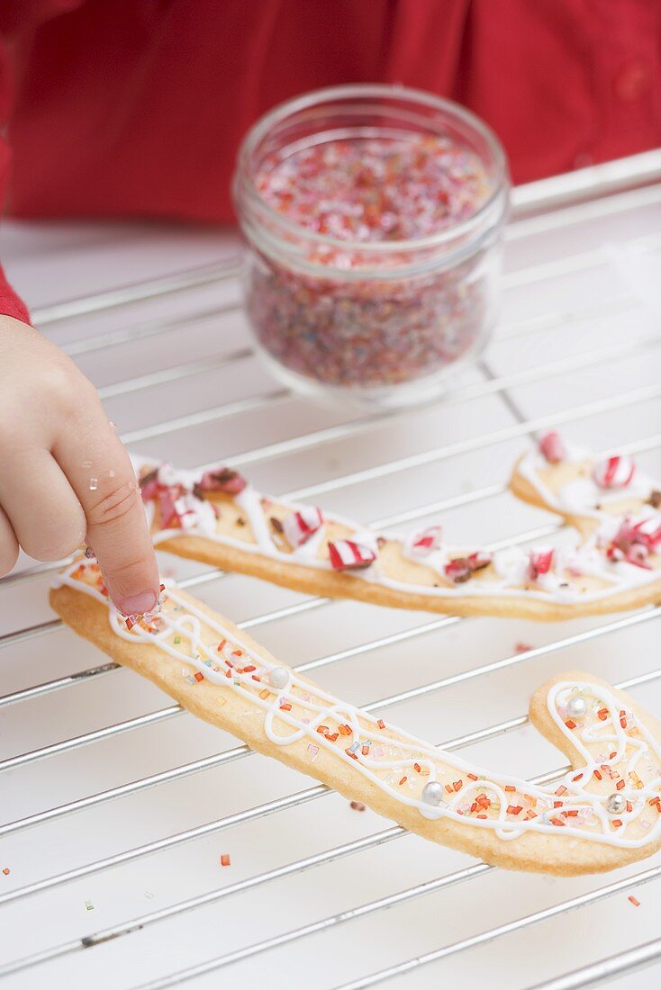 Kind verziert Weihnachtsplätzchen mit Zuckerstreuseln