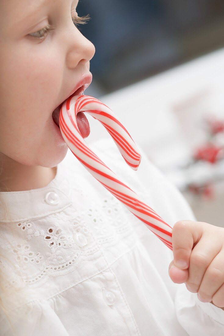 Kleines Mädchen schleckt an Zuckerstange