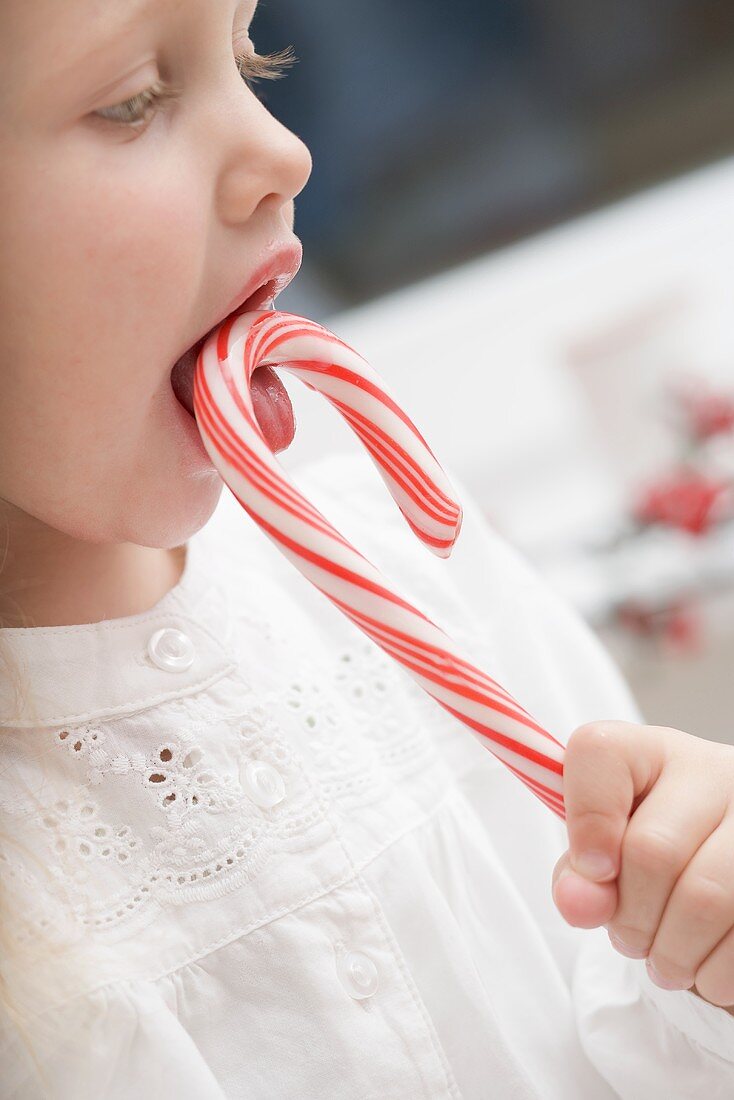 Small girl sucking candy cane
