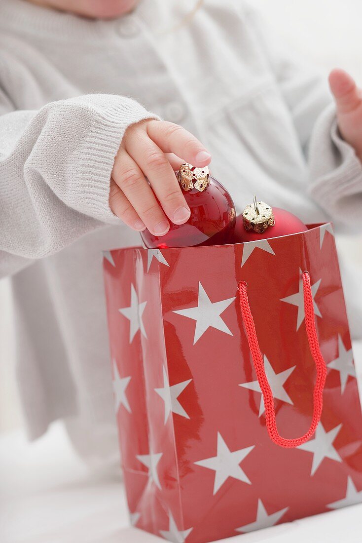 Small girl taking Christmas bauble out of carrier bag